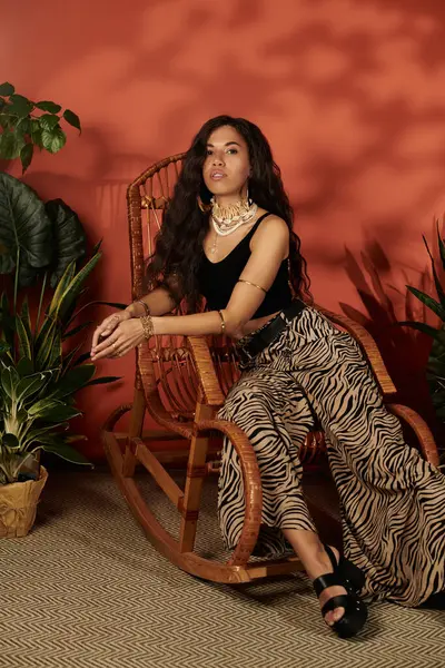 A young woman in summer fashion relaxes in a rocking chair amidst lush plants. — Stock Photo
