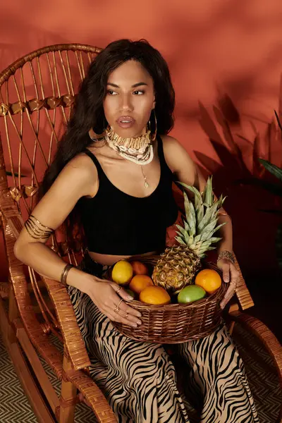 Una donna accattivante in abiti eleganti tiene un cesto di frutta fresca, irradiando gioia estiva. — Foto stock