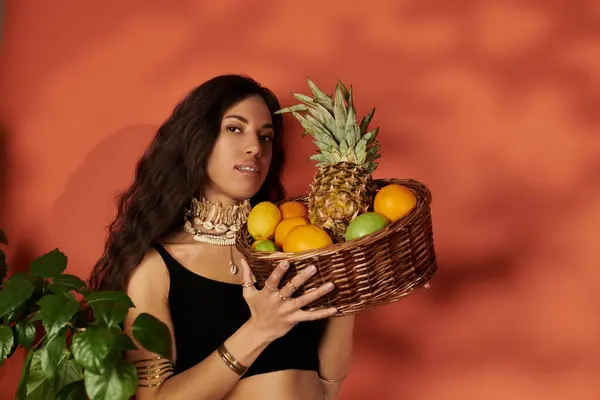 A young woman poses with a basket of tropical fruits, exuding confidence and seasonal charm. — Stock Photo