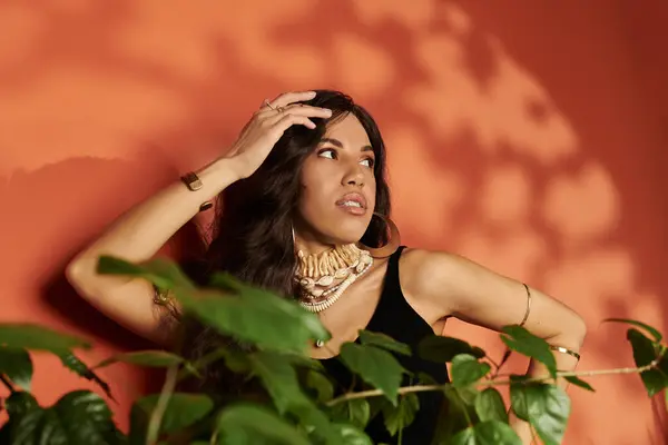 Une jeune femme au style vibrant pose élégamment contre un mur de couleur chaude, rayonnant de confiance. — Photo de stock