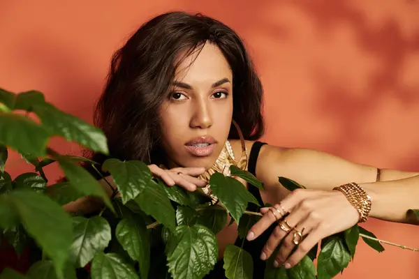 Radiant woman interacts with greenery, showcasing her fashionable style against a warm backdrop. — Stock Photo