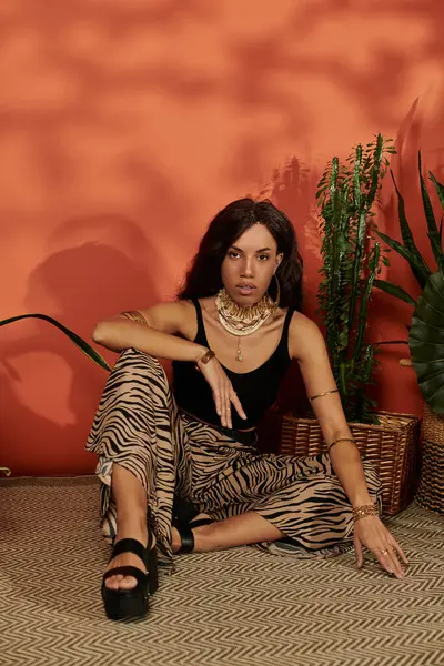 Una giovane donna mette in mostra il suo stile di moda con abiti vibranti mentre si siede in un ambiente lussureggiante. — Foto stock