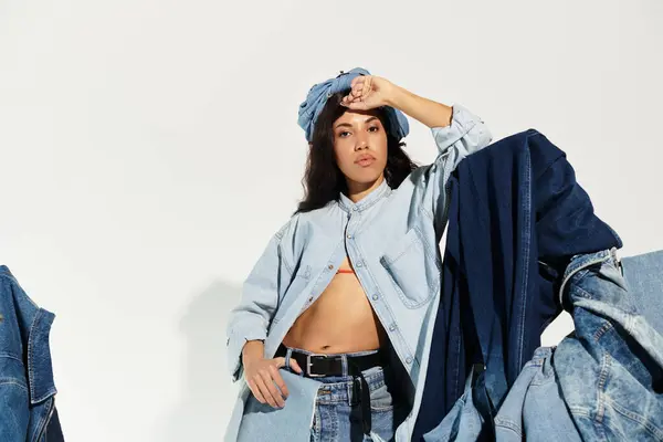 A young woman showcases trendy denim outfits with a stylish pose and vibrant confidence indoors. — Stock Photo