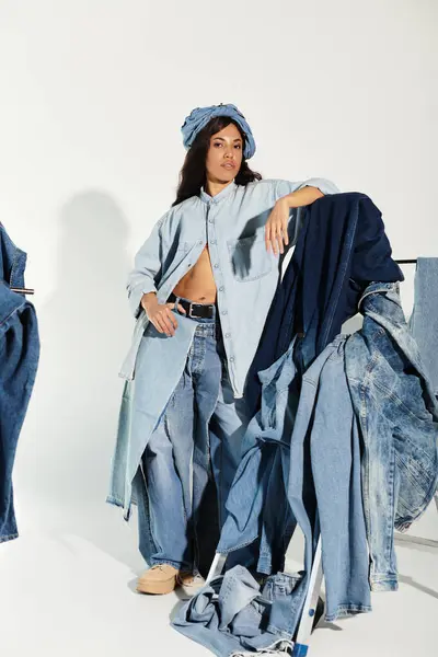 A beautiful young woman showcases unique summer denim styles with artistic flair in a bright space. — Stock Photo