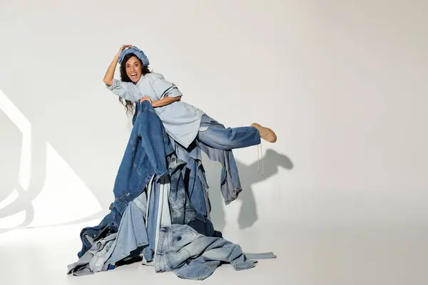 Eine fröhliche junge Frau modelliert verspielte Sommermode vor kreativer Jeansflor-Kulisse. — Stockfoto