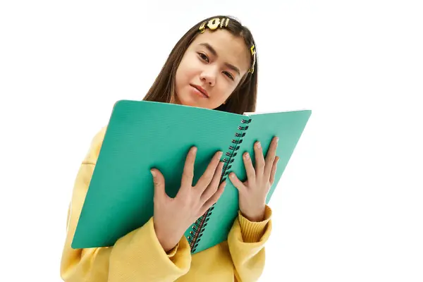 Asian schoolgirl in a chic outfit holds a bright notebook, showcasing her unique style and creativity. — Stock Photo