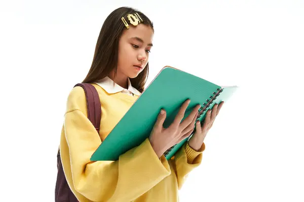 A young asian girl in a trendy school uniform reads a notebook while surrounded by soft light. — Stock Photo
