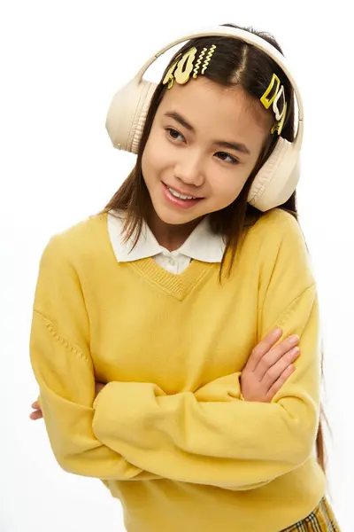 A cheerful young asian schoolgirl with headphones enjoys her time posing in a stylish outfit. — Stock Photo