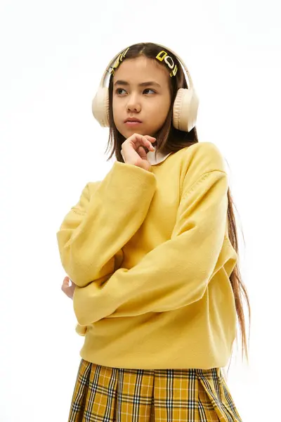 Una colegiala con estilo muestra su uniforme vibrante en un estudio brillante, irradiando confianza. - foto de stock