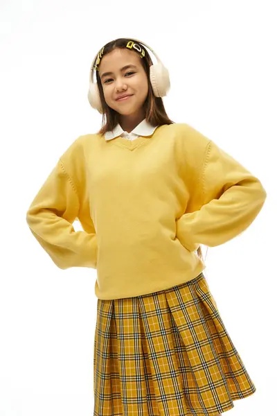A young asian girl showcases her fashionable school uniform in a bright studio environment, smiling. — Stock Photo