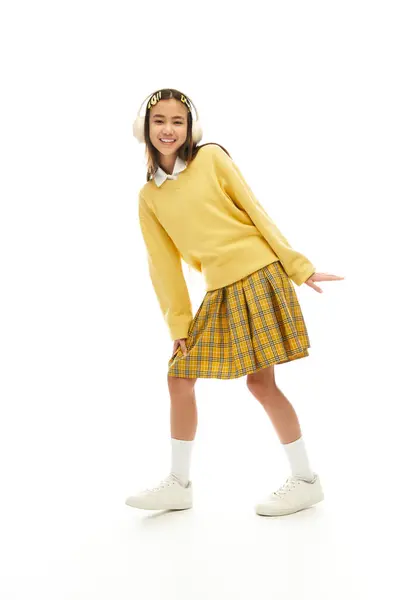 Asian schoolgirl in a vibrant uniform showcases her energetic spirit while posing in a studio. — Stock Photo