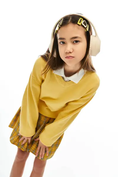 A young girl showcases her fashionable school uniform while standing in a bright studio. — Stock Photo