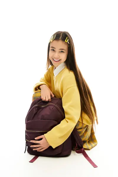 A confident schoolgirl wears a trendy outfit while joyfully embracing her backpack. — Stock Photo