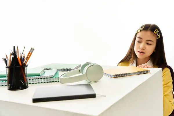 In uno studio elegante, una studentessa asiatica ammira la sua uniforme elegante e materiali di studio. — Foto stock