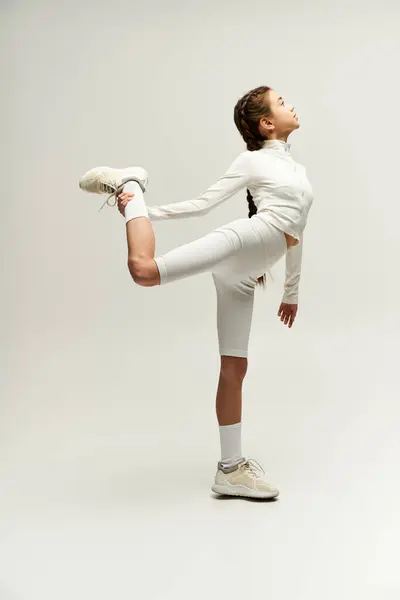 A fit young girl performs a dynamic stretch in sporty clothing, emphasizing her athleticism. — Stock Photo