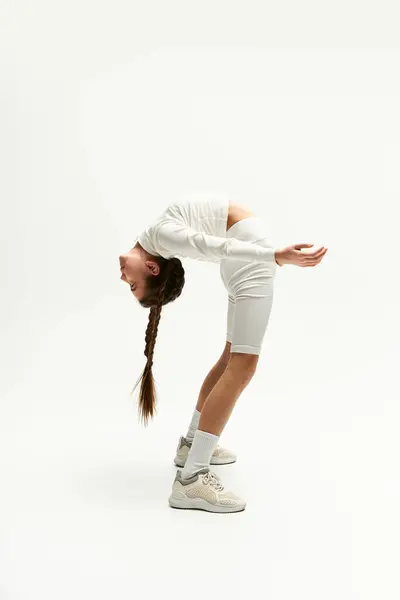 A girl showcases her flexibility in a trendy outfit while posing creatively in a studio. — Stock Photo