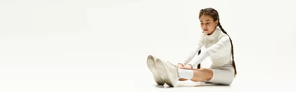 A fit girl in stylish sportswear stretches, highlighting her flexibility in a studio, banner — Stock Photo