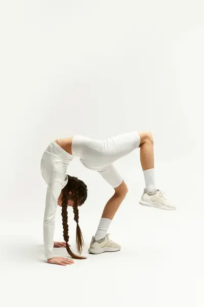 Ein Teenie-Mädchen in trendiger Sportbekleidung demonstriert beeindruckende Flexibilität im Studio-Setting. — Stockfoto
