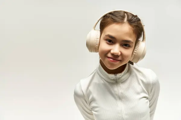 Adatta giovane ragazza con le cuffie posa con fiducia in uno studio vibrante, godendo la sua musica. — Foto stock