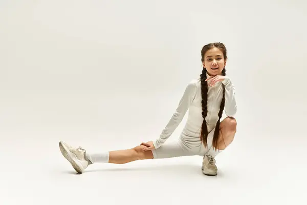 Una ragazza in forma in abbigliamento sportivo elegante si estende con grazia in un ambiente luminoso monolocale. — Foto stock