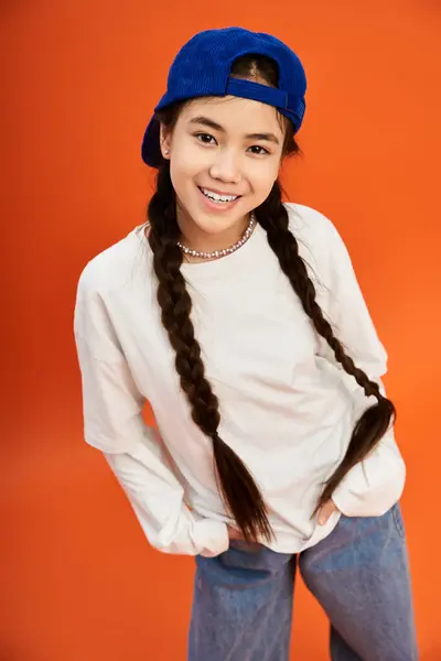 Ein stilvolles Teenie-Mädchen prahlt in einem lebendigen Studio mit leuchtend orangefarbenem Hintergrund mit ihrem einzigartigen Look. — Stockfoto