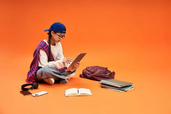 Una ragazza adolescente elegante si impegna nei suoi studi mentre seduto sul pavimento dello studio, godendo il momento. — Foto stock