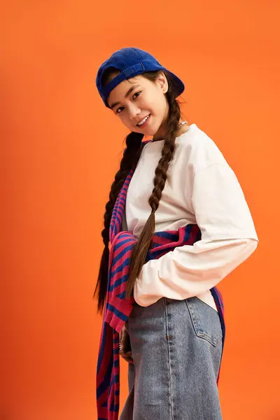 A teenage girl with braids showcases a trendy outfit and playful smile in a studio space. — Stock Photo