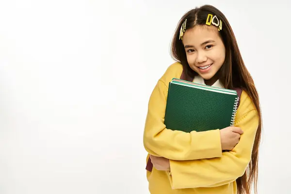 Un adolescente allegro in un abito elegante sorride brillantemente mentre tiene i quaderni chiusi in uno studio. — Foto stock