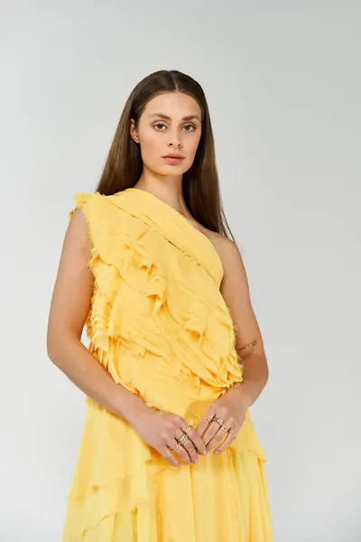 Graceful woman poses confidently in a bright yellow dress, embodying summers vibrant spirit. — Stock Photo