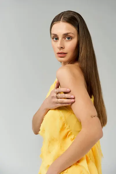 A young woman showcases her radiant beauty in a vibrant yellow dress, exuding summer vibes. — Stock Photo