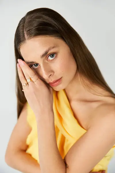 A young woman poses gracefully in a vibrant yellow dress that highlights her charm. — Stock Photo