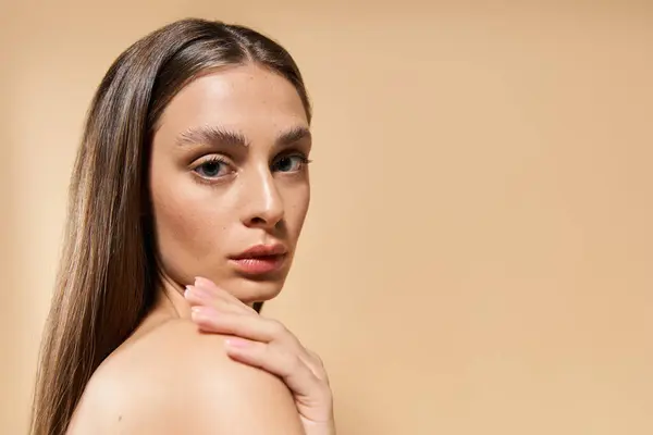 Uma jovem mulher deslumbrante toca suavemente o ombro enquanto exibe uma expressão serena. — Fotografia de Stock