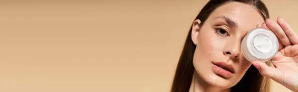 Una splendida giovane donna mette in evidenza un prodotto per la cura della pelle mentre trasuda vibrazioni estive ed eleganza. — Foto stock