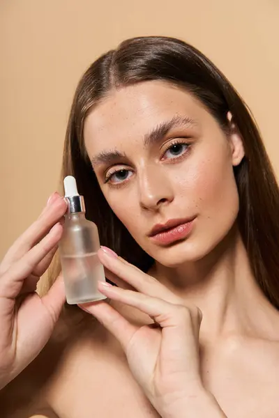 Eine schöne junge Frau hält ein Hautpflegeserum in der Hand, das sommerliche Stimmung und strahlende Gesundheit verkörpert. — Stockfoto
