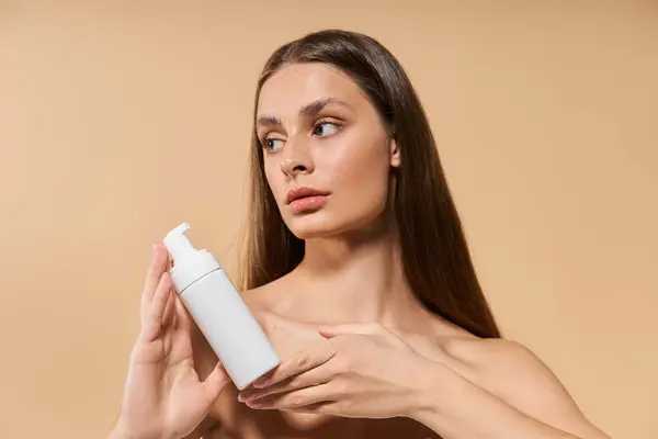 Молодая женщина демонстрирует продукт по уходу за кожей с уверенным выражением лица среди летней атмосферы. — стоковое фото