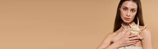 Junge Frau zeigt einzigartigen Schmuck und verkörpert gleichzeitig Sommermode vor weichem, warmen Hintergrund. — Stockfoto