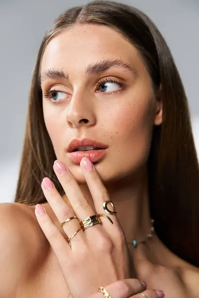 Radiant young woman showcases her beauty and unique jewelry against a soft, artistic backdrop. — Stock Photo