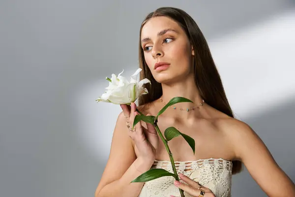 Une belle jeune femme tient une fleur délicate tout en incarnant l'esprit vibrant des étés. — Photo de stock