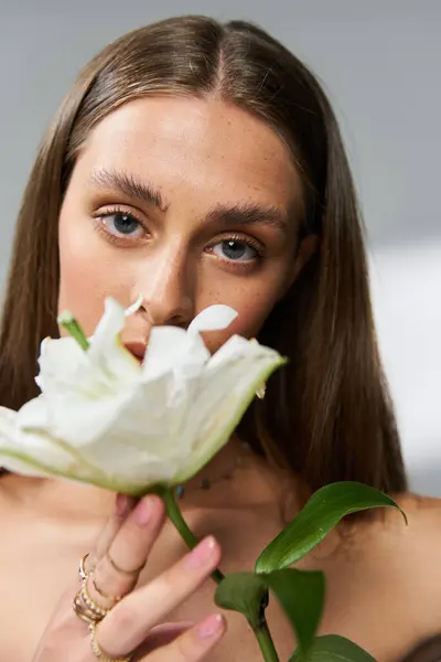 A beautiful woman holds a white flower to her face, radiating summer charm. — Stock Photo