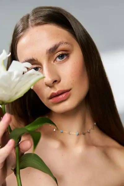 Jeune femme embrasse l'élégance estivale tout en tenant une belle fleur blanche, rayonnant de charme. — Photo de stock