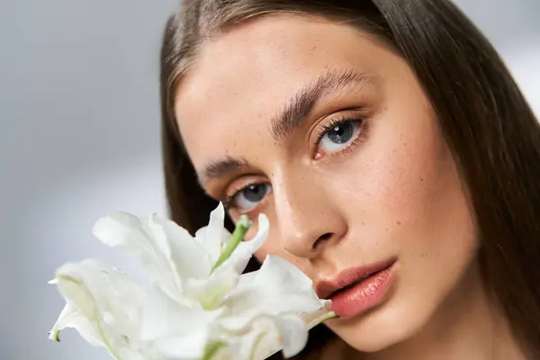 Eine junge Frau mit markanten Gesichtszügen hält weiße Blumen in der Hand und genießt die sommerliche Wärme. — Stockfoto