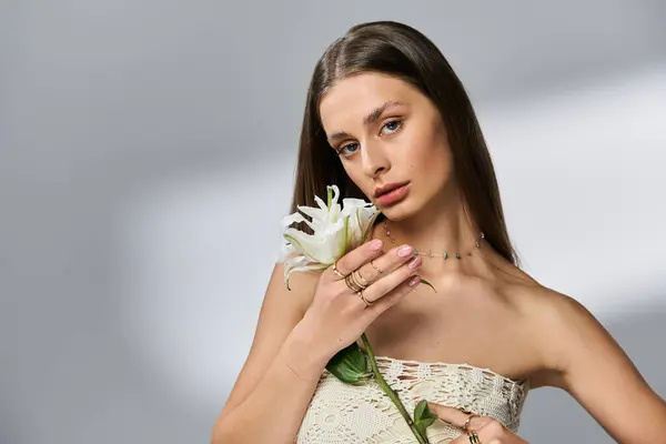 Une jeune femme captive par sa beauté sereine, tenant une fleur, incarnant le charme des étés. — Photo de stock