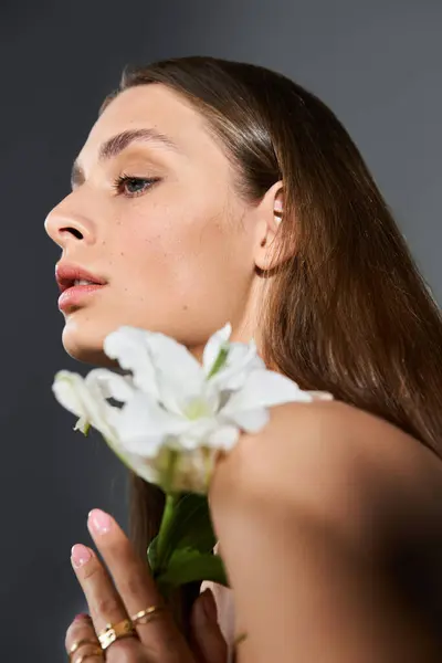A beautiful woman gently holds a white flower, embodying grace and tranquility in summer light. — Stock Photo