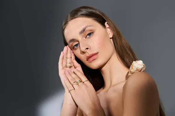 Una splendida giovane donna mette in mostra anelli eleganti mentre posa con grazia in luce morbida. — Foto stock
