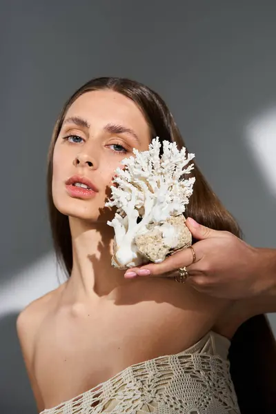 A graceful woman holds a beautiful coral, embodying summer elegance. — Stock Photo