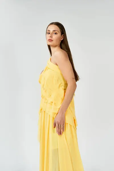 Jeune femme brille dans une robe jaune vif, rayonnant d'élégance et de confiance. — Photo de stock