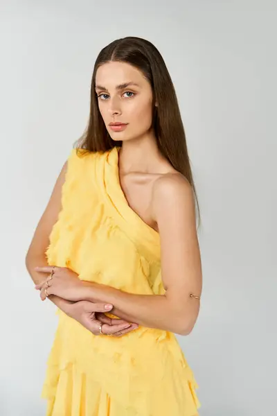 Eine schöne junge Frau präsentiert Sommermode in einem atemberaubenden gelben Kleid, das Zuversicht ausstrahlt. — Stockfoto