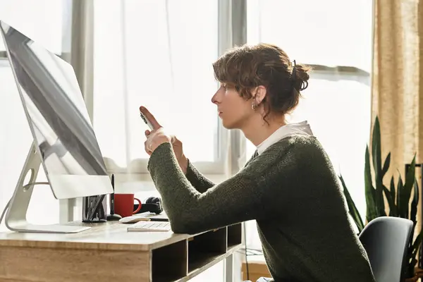 A young man studies at his desk by a window, focused on his smartphone. — Stock Photo