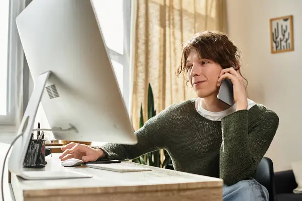 Un joven en casa usa una computadora y un teléfono para mejorar sus estudios mientras contempla ideas. - foto de stock