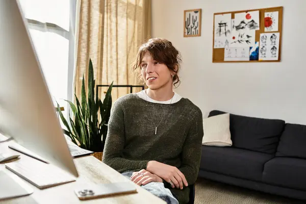 Junger Mann sitzt gemütlich zu Hause und studiert intensiv, während er von Kunstwerken und Pflanzen umgeben ist. — Stockfoto